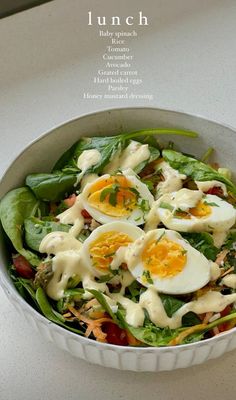 a salad with hard boiled eggs and spinach in a white bowl on a counter