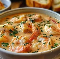 a bowl of shrimp chowee with bread in the background