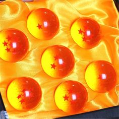 eight orange balls with red stars are in an egg carton on a yellow cloth