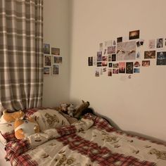 there is a bed with many pictures on the wall and teddy bears laying on it