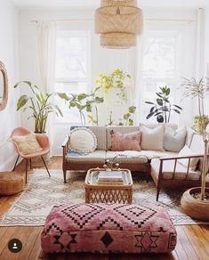 a living room filled with lots of furniture and plants on top of wooden flooring