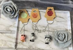 four keychains with cartoon characters on them sitting on a marble tray next to a flower