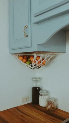 a kitchen with blue cabinets and wood counter tops is pictured in this image, there are fruit on the shelf above the sink