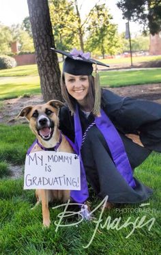 a woman sitting in the grass with her dog wearing a graduation gown and holding a sign that says, my mommy is graduating