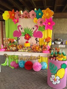 a table topped with lots of food next to a wall covered in flowers and balloons