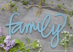 a wooden sign that says family on it next to some flowers and branches with leaves