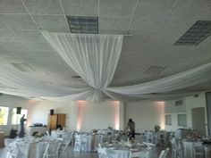 a banquet room with white linen draped over the ceiling and tables set up for an event