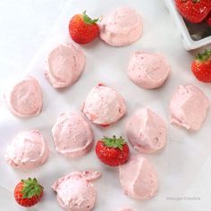 strawberries and whipped cream are arranged on a white surface next to a bowl of strawberries