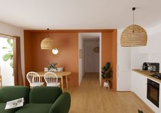 a living room filled with furniture next to a kitchen and dining room table in front of an open door