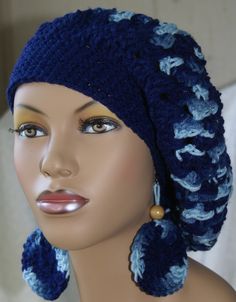 a mannequin wearing a crocheted blue hat and earring with beads