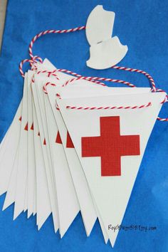 some white paper with red cross on it and string hanging from the top, next to a blue background