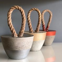 three cement bowls with rope wrapped around them on a white countertop, in front of a gray wall