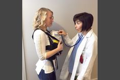 two women in white lab coats standing next to each other, one holding a stethoscope