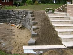 concrete steps leading up to a house with landscaping tools in the foreground and dirt on the ground