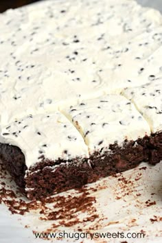 a cake with white frosting and chocolate sprinkles sitting on top of it