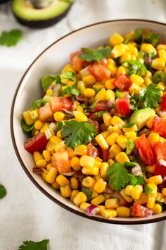 corn salad with cilantro and avocado in a bowl on a table