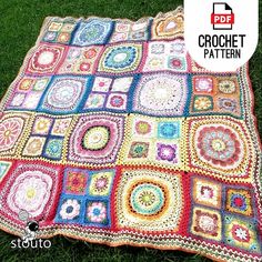 a crocheted blanket is laying on the grass with it's border made out of squares