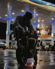 a man riding on the back of a motorcycle in front of a gas station at night