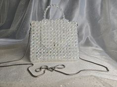 Handmade Crystal White Beaded Mini Bag with Silver-Toned Hardware This elegant handbag, crafted from crystal white beads, features silver-toned hardware and a 47-inch removable chain. The magnetic closure adds convenience and ease of use. Our bags are 100% handmade. Each bag is unique and crafted with love for our customers. It takes 3-5 days to create one bag. A perfect gift for women, friend, family member or loved one. Ideal for any celebration, event, wedding or birthday party. This unique a Silver Beaded Crystal Bags, Silver Crystal Beaded Bags, White Crystal, One Bag, Beaded Bags, White Beads, Beaded Jewelry Diy, Clutch Handbag, Chain Lengths