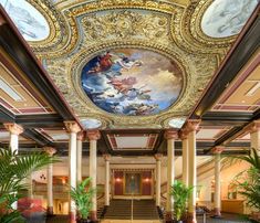 an ornately decorated lobby with paintings on the ceiling and columns, along with potted plants