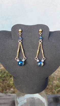 a pair of blue and gold earrings sitting on top of a mannequin