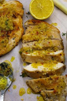 sliced chicken with herbs and lemons on the side