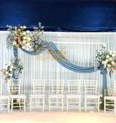 a wedding ceremony setup with blue drapes and white chairs