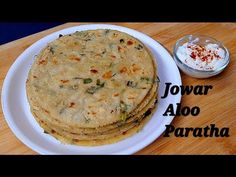 three flat breads on a white plate next to a bowl of yogurt