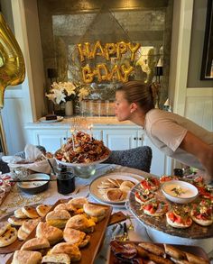 a woman standing over a table filled with food