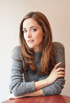 a woman sitting at a wooden table with her arms crossed and looking off to the side