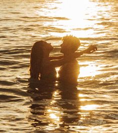 two people are in the water with their arms around each other