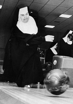 two women in black and white are bowling on a bowling alley with one wearing a nun costume