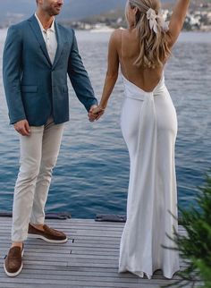 a man and woman holding hands while standing on a dock