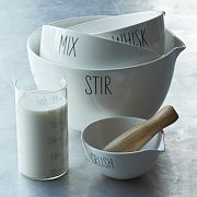 a measuring cup with a wooden spoon in front of it and another measuring bowl next to it