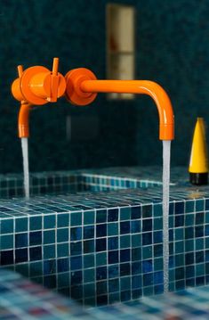 an orange faucet in a blue tiled bathroom