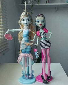 two dolls standing next to each other on a table