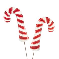 two red and white candy canes sitting on top of each other in front of a white background