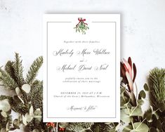 the wedding card is surrounded by greenery and pine cones, with a red bow on top