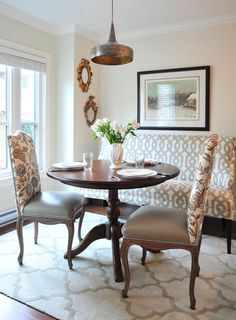 a dinning room table with chairs and a bench in front of a large window