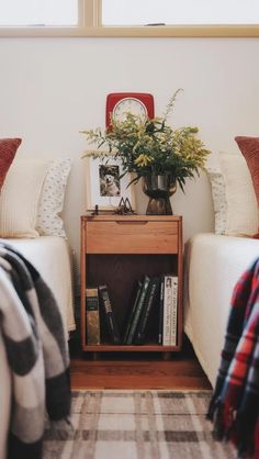 a nightstand with books and flowers on it next to two twin beds in a bedroom