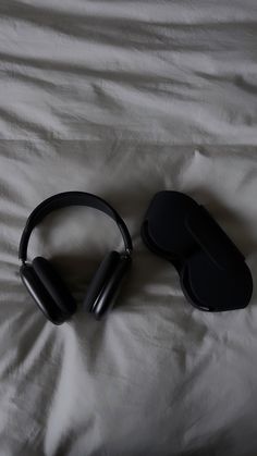 two black headphones laying on top of a white sheet covered bed next to each other