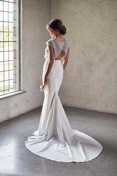 a woman in a white wedding dress looking down at the floor with her back to the camera