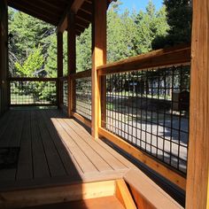 a wooden porch with metal railings and trees in the background