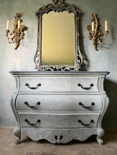 an antique dresser with mirror and candles on it