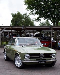 an old green car parked in a parking lot