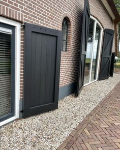 the side of a brick building with black shutters