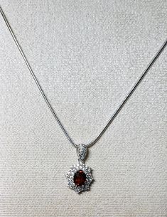 "Gemstone: genuine natural oval cut spessartite garnet Size: 7mm x 5mm Weight: .64ct approx Accent stones: round cut white cubic zirconia Total length including bail: 3/4\" Total width: 1/2\" Metal: .925 stamped sterling silver, rhodium plated  Chain: 18\" snake chain, 1.5mm wide, with lobster clasp, rhodium plated  Total weight: 2.3g" Elegant Garnet Jewelry With Round Stone, Elegant Garnet Round Jewelry, Oval Diamond Jewelry With Stones, Elegant Garnet Jewelry, Round Garnet Gemstone Jewelry, Oval Cubic Zirconia Jewelry With Stones, Oval Cubic Zirconia Jewelry, Classic Garnet Round Stone Jewelry, Classic Garnet Jewelry With Gemstone Accents