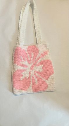 a pink and white bag sitting on top of a bed