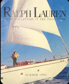 a man standing on top of a sailboat in the middle of the ocean with it's sails down