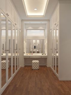 an empty white bathroom with wooden floors and mirrors on the wall, along with two sinks